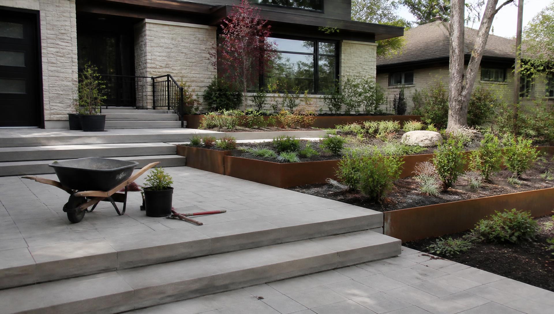 Front yard construction staging with finished paving corten steel planters and newly planted shrubs. Images and Photos created by www.house-and-garden-designs.com
